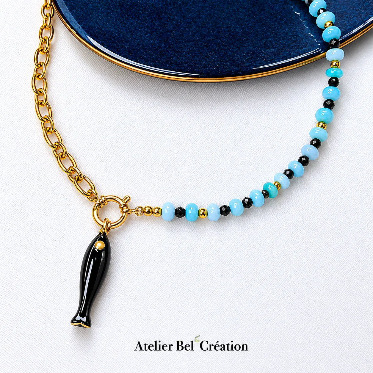 Collier Atelier Bel’Création avec perles bleues, chaîne dorée et pendentif poisson noir